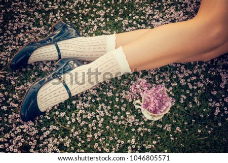 Girl legs lying on the grass with a fine bone china teacup and a bouquet of lilac flowers - Spring flowers - Shabby chic blossom