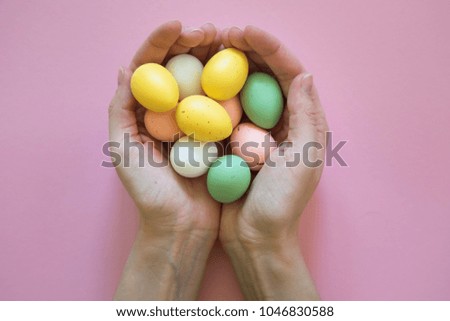 Colorful easter eggs in hands on pink background