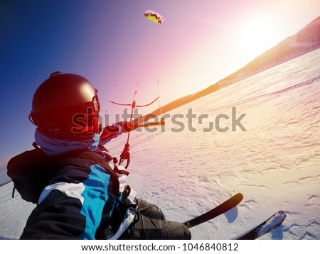 Selfie action camera Skier with kite rides on frozen lake on free ride. Russia. Snowkite sunset. Royalty-Free Stock Photo #1046840812
