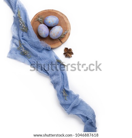 Easter composition made of blue dyed speckled eggs, wood slice, pastel colored textile and floral elements. Flat lay.