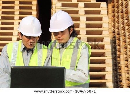 industry manufacturing . workers using laptop with stacking pallet background