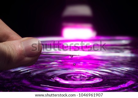 A needle over water tank for preparations to photograph a water droplet with light pink colors.