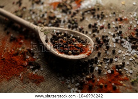 Black and white pepper peas, sea salt, red pepper powder, cloves, spices in a spoon on a wooden background. Various colorful spices close up background. Selective focus. photo for the menu. Top view