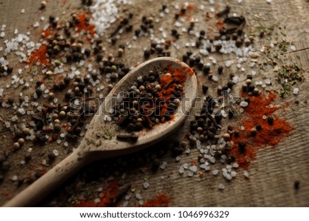 Black and white pepper peas, sea salt, red pepper powder, cloves, spices in a spoon on a wooden background. Various colorful spices close up background. Selective focus. photo for the menu. Top view