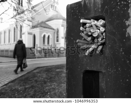 The element of the fence in which the parishioners of the Lutheran Church leave cigarette butts. Grayscale photo.