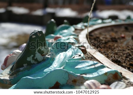 blue and green tattered frog statue 