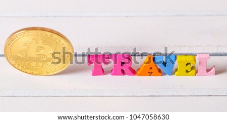 Bitcoin cryptocurrency with colorful 'TRAVEL' word on white wooden table top