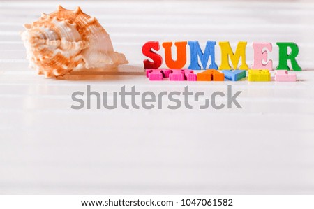Sea shell with colorful 'SUMMER TRAVEL' phrase on white wooden table top