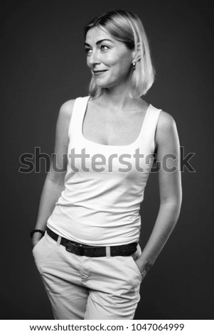 Studio shot of beautiful businesswoman with short hair against black background in black and white