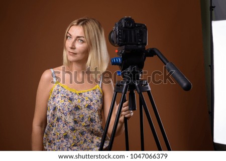 Studio shot of beautiful businesswoman with short blond hair against brown background