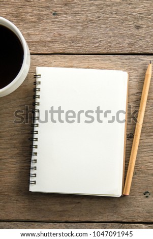 Top view of blank notebook with white coffee and natural light on wooden table.