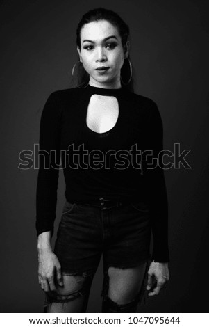 Studio shot of young beautiful Asian transgender woman against black background in black and white