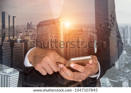 Double exposure of businessman using the phone with cityscape background