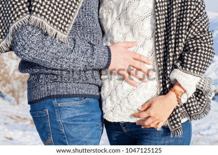 Close up picture parents to be holding hands outdoor on a sunny winter day