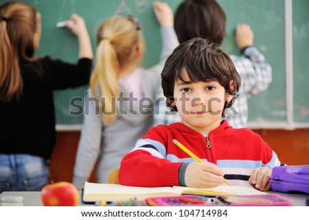 Cute little schoolboy drawing an apple and looking at camera