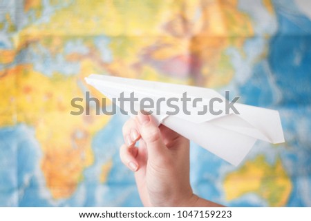 paper airplane in hand on world map background