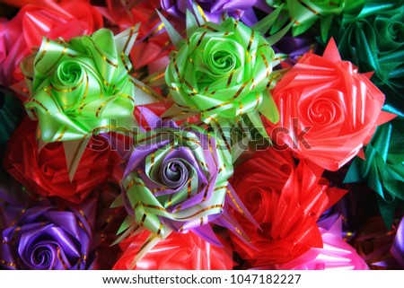 Colorful almsgiving ribbon-flowers. Close up colorful ribbon flowers and coins folding with mulberry paper for giving alms to make merit in Thai's religious traditional. It is a beautiful picture.
