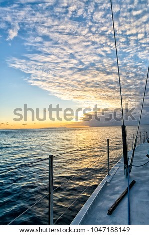 View of a beautiful orange sunset from the deck of a sailing boat in the Australian sea near the Whitsunday's islands. Concept for quite, freedom and adventure