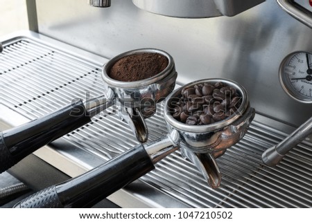 An two espresso handle filled with ground coffee and seed located at the coffee machine at cafe