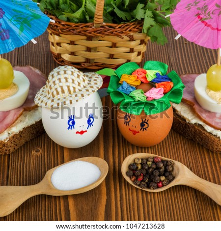 Cute handmade eggs, as little people, with funny painted faces in hats on a wooden background. Easter holiday concept. Square. Close-up.