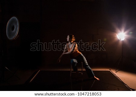 Woman in a yellow t-shirt in a dark Studio illuminated by colored spotlights during photoshoot