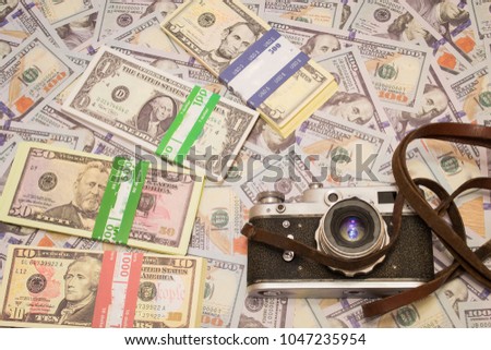 
A retro camera on the background of money. Hobby and business in one photo
