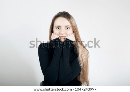 Portrait of a girl in a black sweater with hands near face