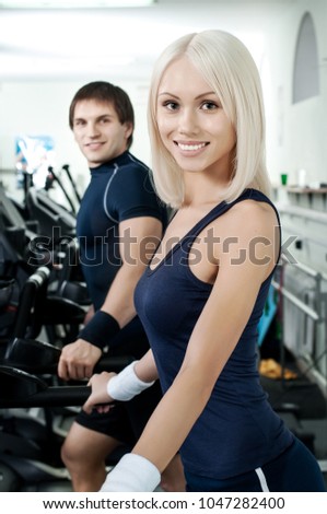 young fitness woman in gym perform exercise on running tracks, vertical photo