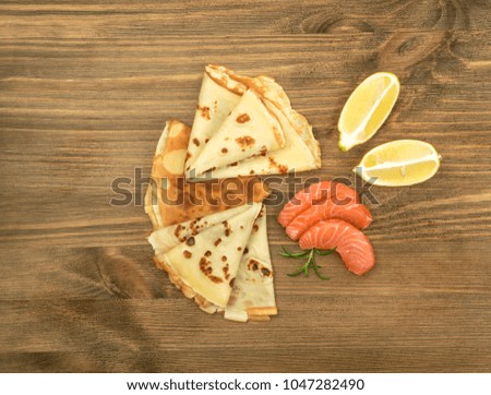 Crepes with Raw Sliced Salmon Fillet. Thick Pieces of Red Trout with Pancakes on Dark Wooden Background