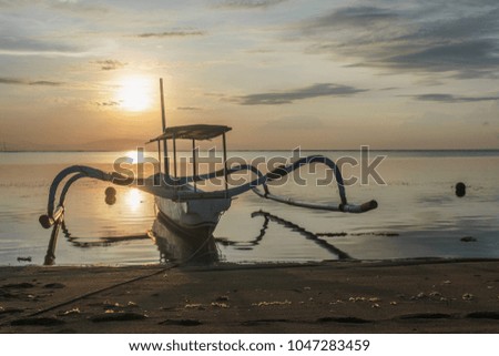Beautiful sunrise on the calm beach with boats in Bali