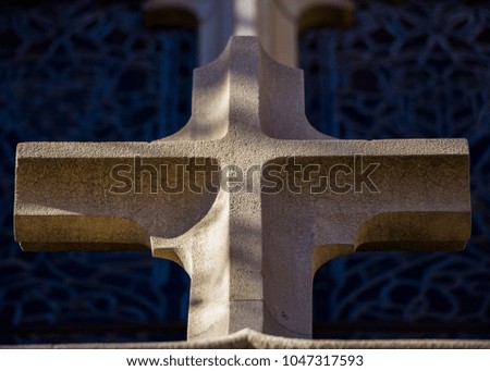 Exterior stone cross with stained glass background.