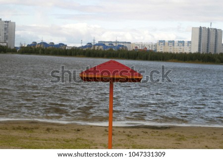 Beach umbrella near the water in the form of a mushroom. Summer and autumn background 