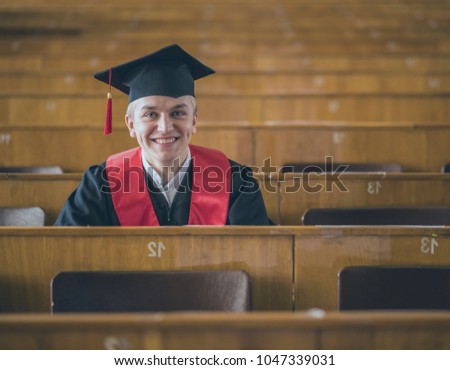 a young boy in the mantle of a master's degree in higher education smiles