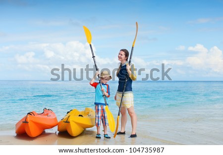 Happy mother and son at beach preparing for kayaking