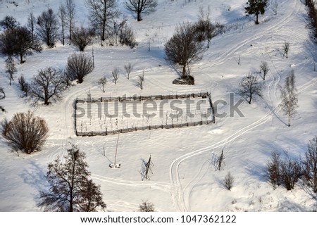 Geometric shapes seen on snow white. A picture of the air in which the fences and forests are seen.