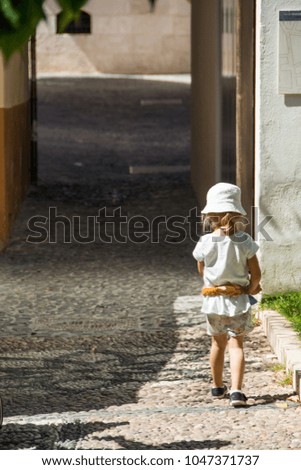Kid walking alone, empty narrow street