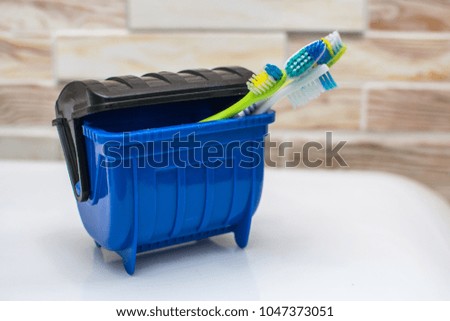 Toothbrushes in a blue trash can, lots of germs so threw away
