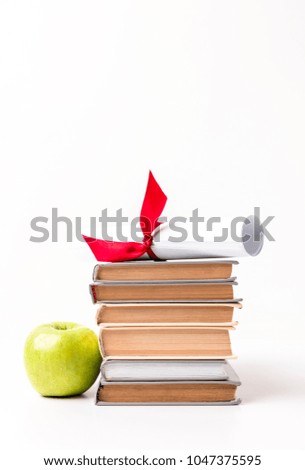 Diploma on pile of books and apple isolated on white