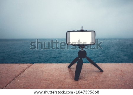 smartphone is taking a video of sea on a small tripod