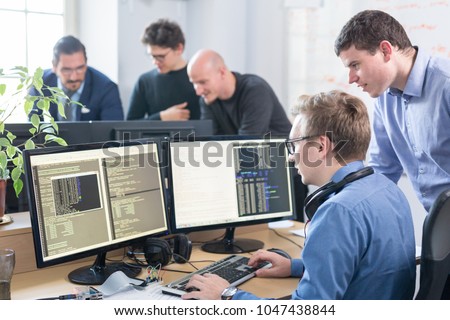 Startup business and entrepreneurship problem solving. Young AI programmers and IT software developers team brainstorming and programming on desktop computer in startup company share office space.
