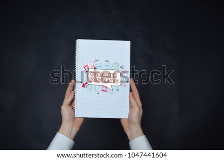 In the hands of a businessman a notebook with the inscription:CUSTOMER EXPERIENCE