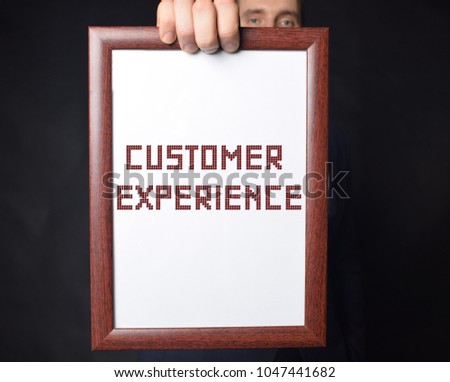 In the hands of a businessman a frame with the inscription:CUSTOMER EXPERIENCE