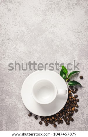 Empty white cup and coffee beans on concrete background. Top view, space for text.