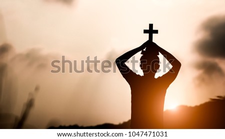 Young man holding cross and holy Bible on head