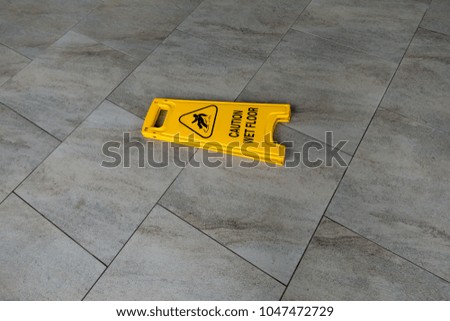 A yellow caution  wet floor sign laying on the floor