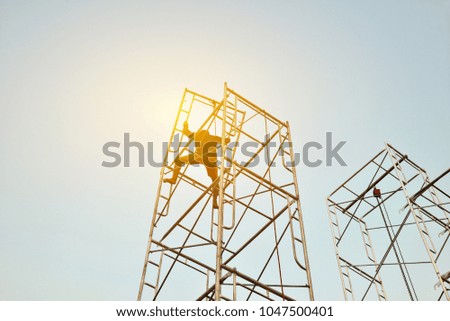 Workers setup scaffolding with sunset background