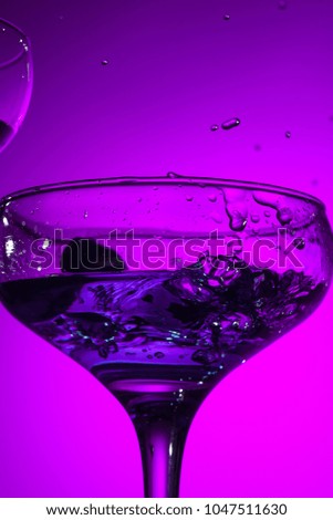The wine stuffed glasse with cocktail standing on the table at studio. Vivid bright colored lighting. Trendy in 2018 Ultra Violet Light Bulb. Art decoration with tone of mystic color