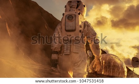 Courageous Astronaut in the Space Suit Explores Red Planet Mars Covered in Mist. Shelter in background. Space Travel, Colonization Concept.