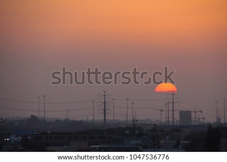 Spectacular sunset in an urban landscape - a fireball and power poles silhouettes, Energy Concept. Soft warm peach- grey- purple colors gradient. copy space 