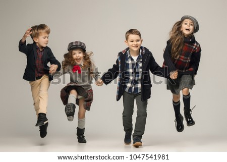 The group of happy smiling teen girls and boys on a pastel studio background. Stylish young teen girls posing at studio. Classic autumn style. Teen and kids fashion concept. children's fasion concept Royalty-Free Stock Photo #1047541981